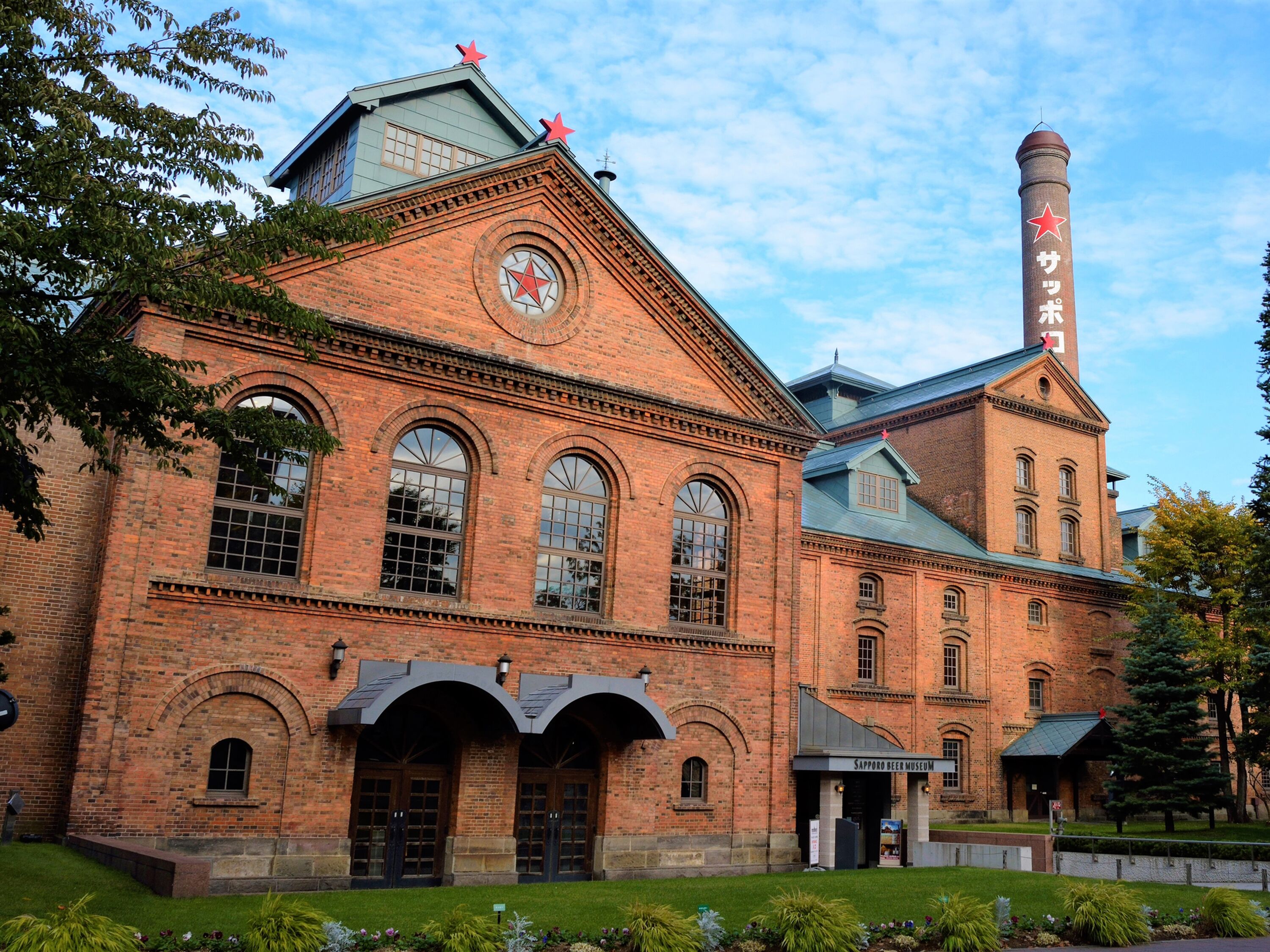 A historic brick building with arched windows and a prominent tower with a red star.