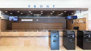 Ein Empfangsbereich mit einer Marmor-Theke, einer Uhr und einem Schild mit der Aufschrift 'FRONT'.