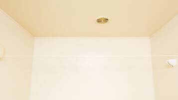 A bathroom with a beige wall, a ceiling vent, and a towel rack.