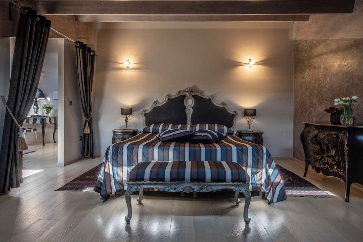 A bedroom with a large bed, a bench, and two bedside tables with lamps.