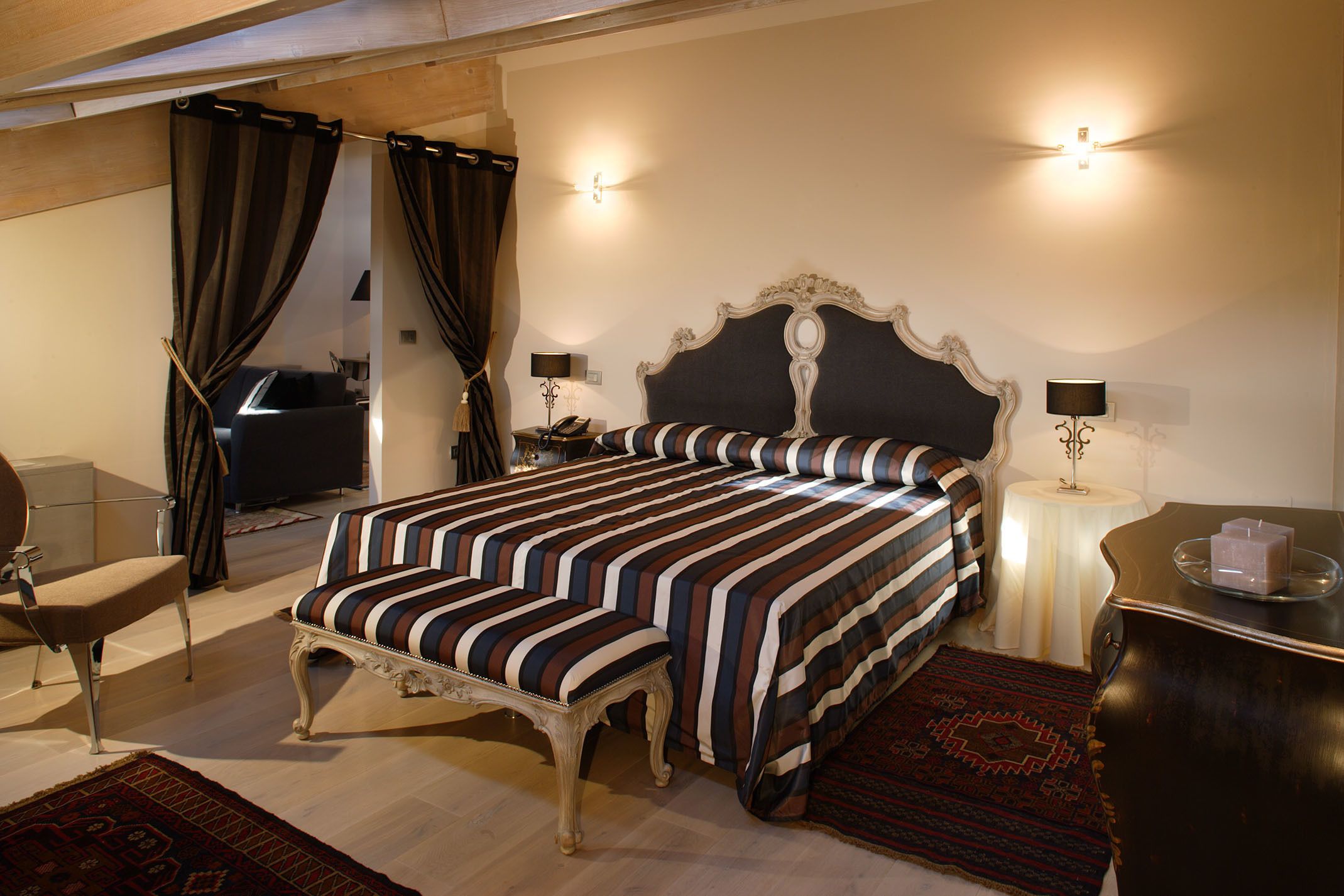 Ein Schlafzimmer mit einem großen Bett, einem Sessel, einem kleinen Tisch und einem Nachttisch.