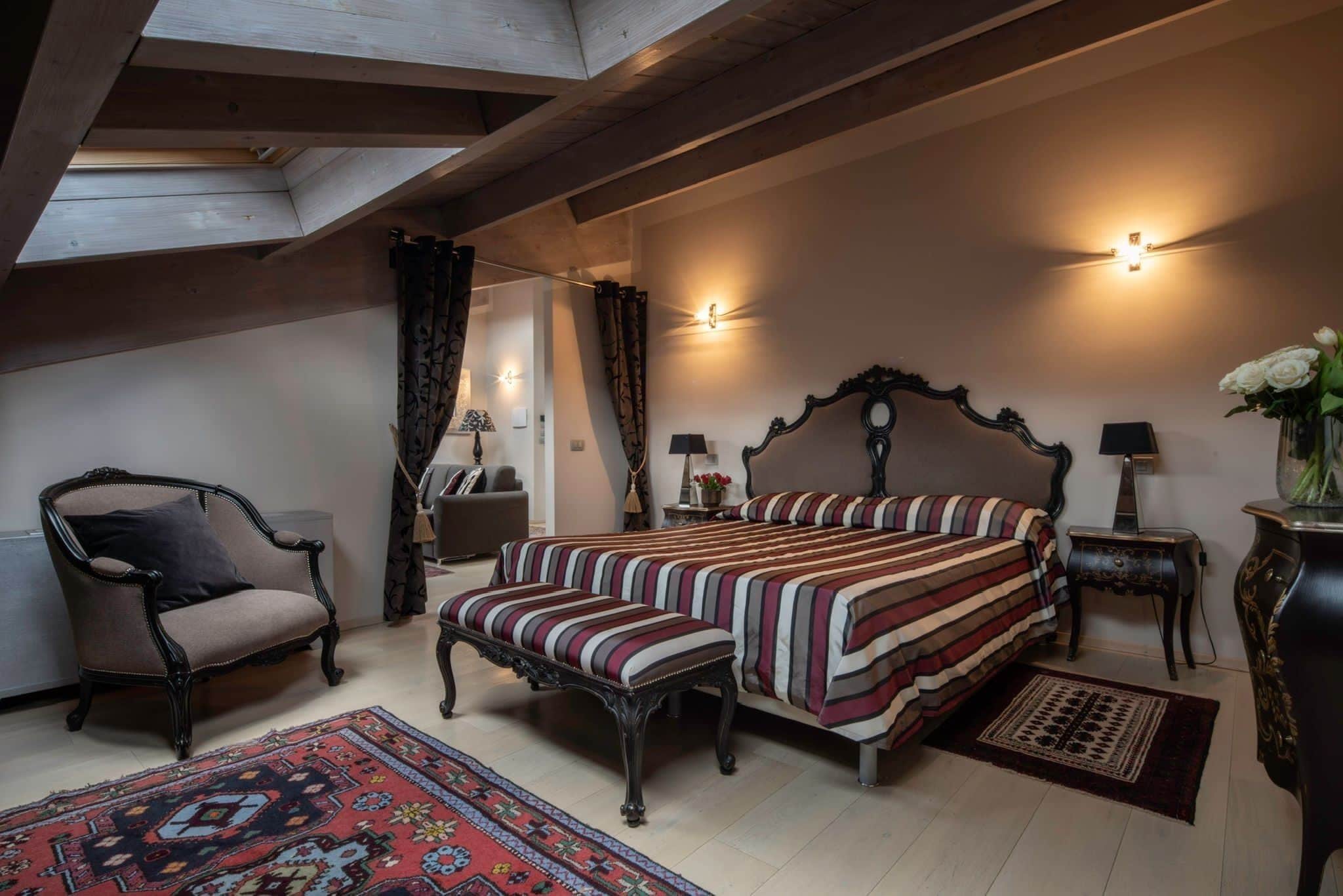 Un dormitorio con una cama grande, una silla, una mesita y una lámpara.