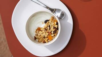 A table with a bowl of yogurt and granola, and a bowl of fruit salad on a napkin.