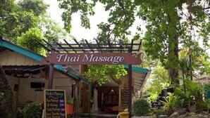 A Thai massage center with a signboard, a menu board, and a small pool area.