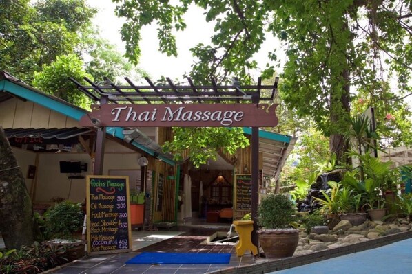 A Thai massage center with a signboard, a menu board, and a small pool area.