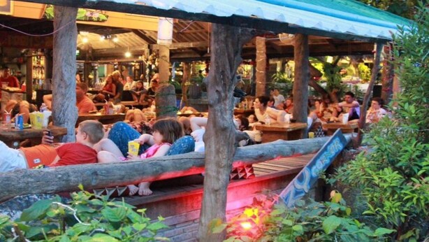 An outdoor restaurant with wooden tables and a covered seating area.