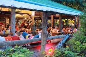 An outdoor restaurant with wooden tables and a covered seating area.