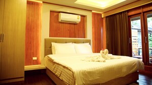 A bedroom with a large bed, wooden paneling, an air conditioning unit, and a view of the outdoors.
