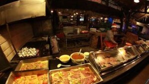 A buffet with various food items and a person in Santa attire in the background.