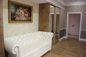 Relax in a stylish room with a tufted sofa, framed artwork, and patterned wallpaper.