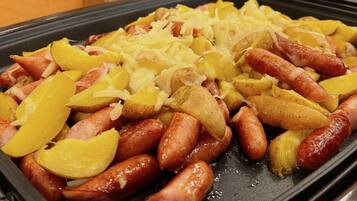 A tray of food with sausages, potatoes, and cheese.