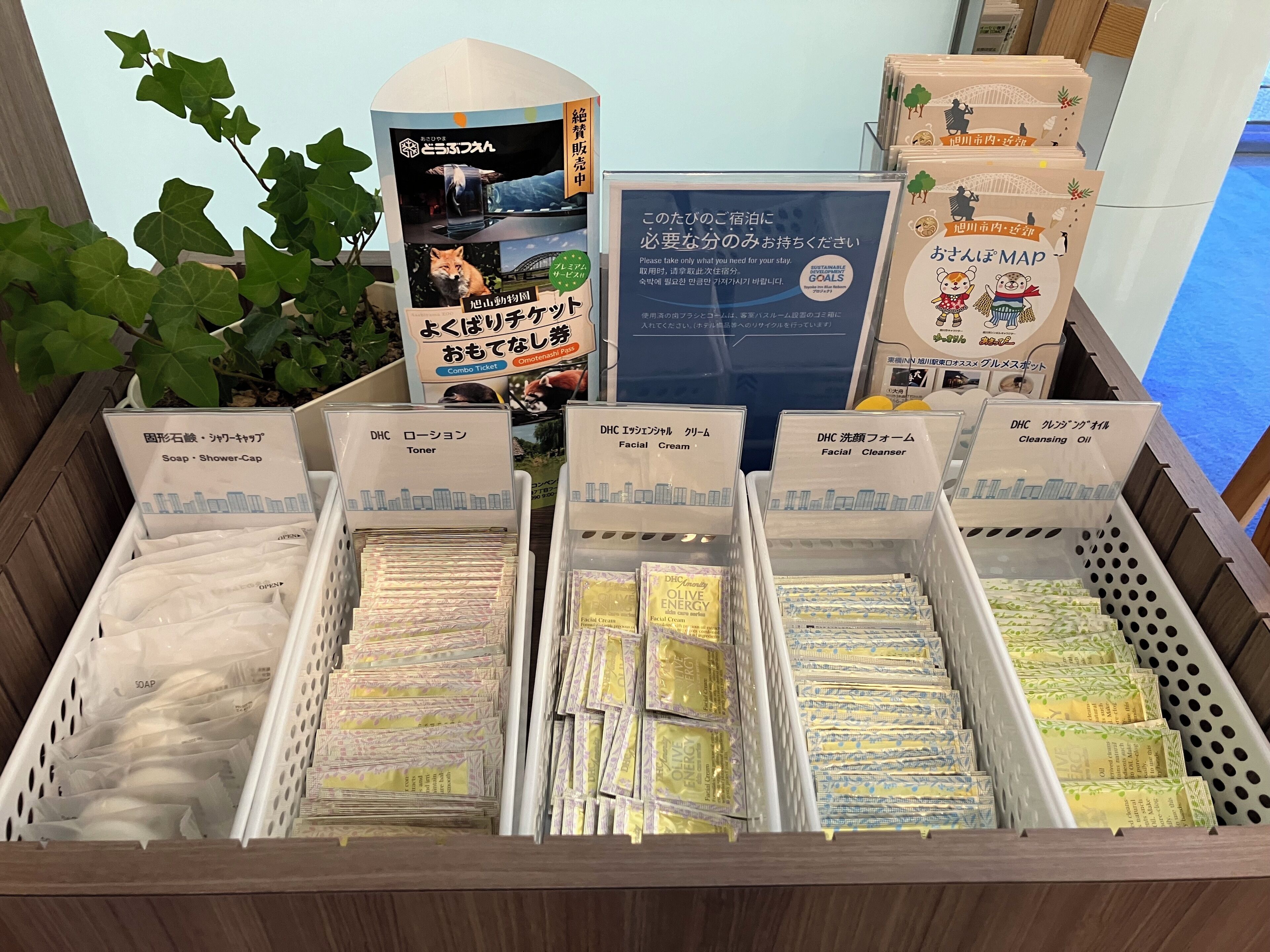 A display of hotel amenities including soap, shower caps, toners, facial creams, and cleansing oils.