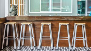Un coin bar avec quatre tabourets en bois et une statue de hibou décorative.