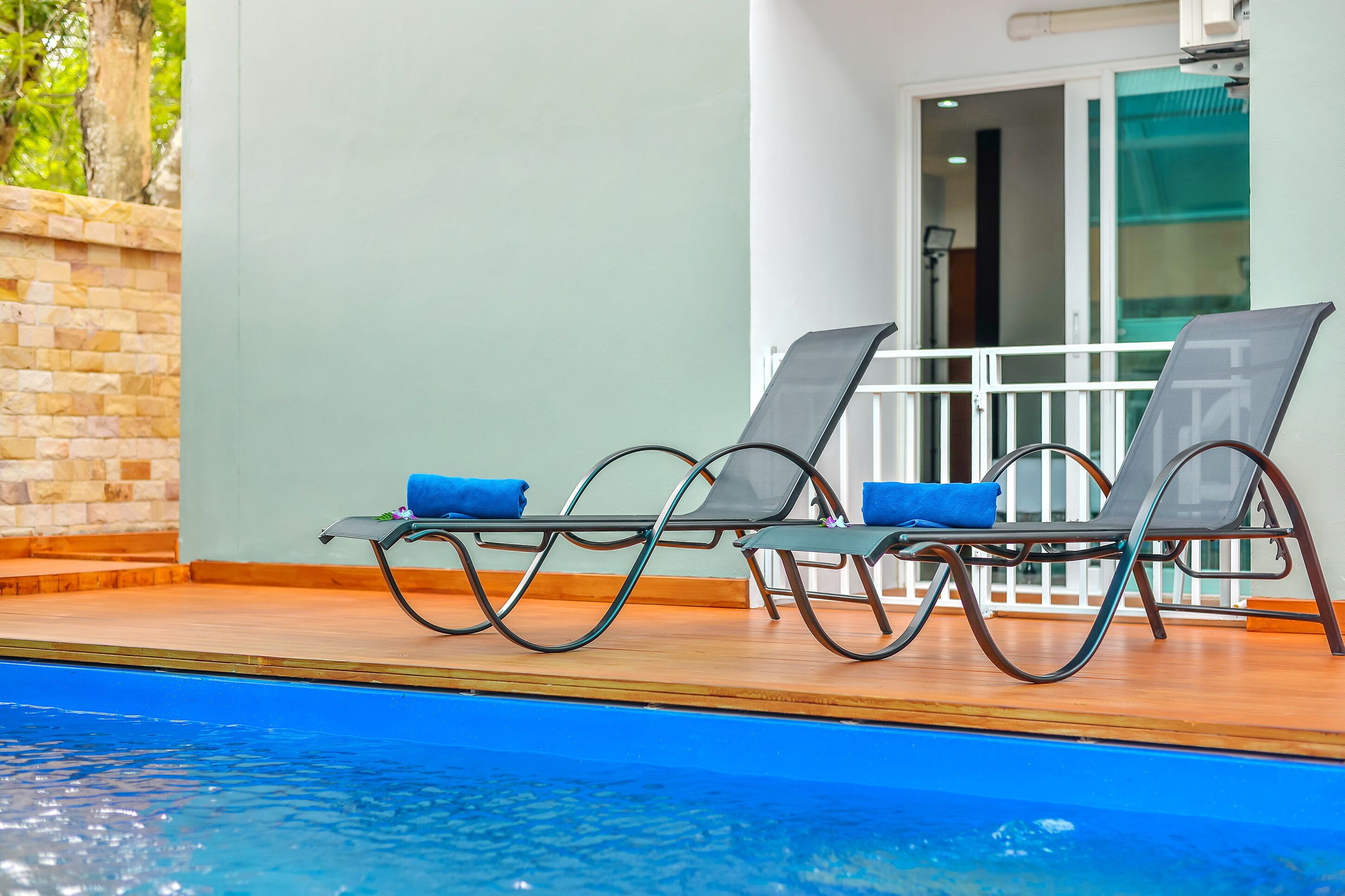 A poolside area with two lounge chairs and a wooden deck.