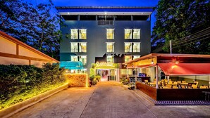 Un hôtel avec une enseigne au néon, un espace extérieur abrité avec des sièges et une entrée bien éclairée.