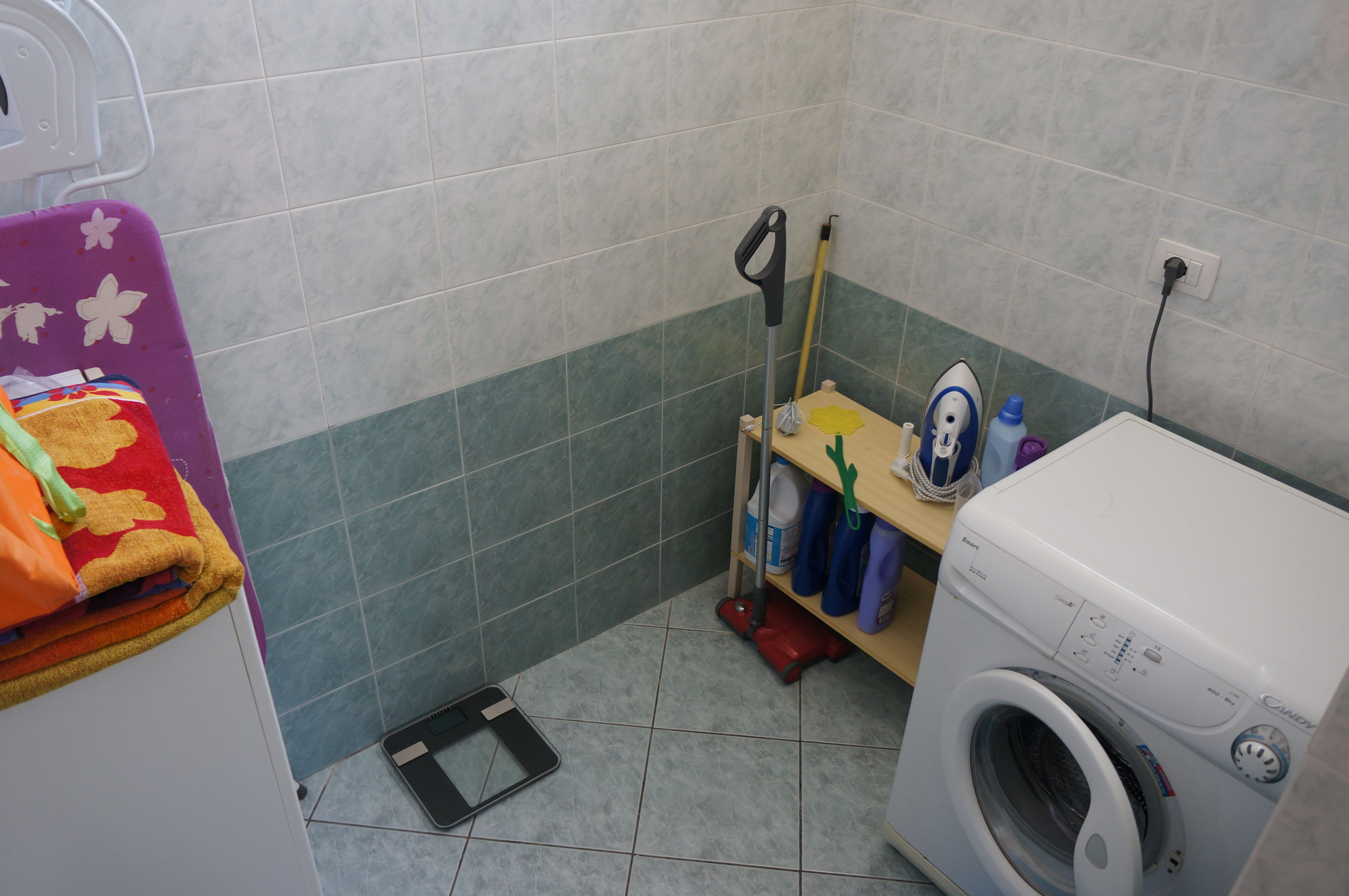 A laundry area with a washing machine, a mop, and cleaning supplies.