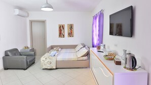 A modern bedroom with a bed, a sofa, a TV, and a coffee maker. - IzzHome Regina Margherita (Pula)