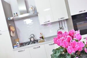Una cocina moderna con armarios blancos, una campana de acero inoxidable y una estufa a gas.