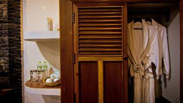 Une armoire en bois avec un miroir, une robe suspendue à l’intérieur et une étagère contenant des articles de toilette.