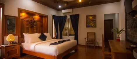 A bedroom with a wooden bed, a nightstand, a desk, and a chair.