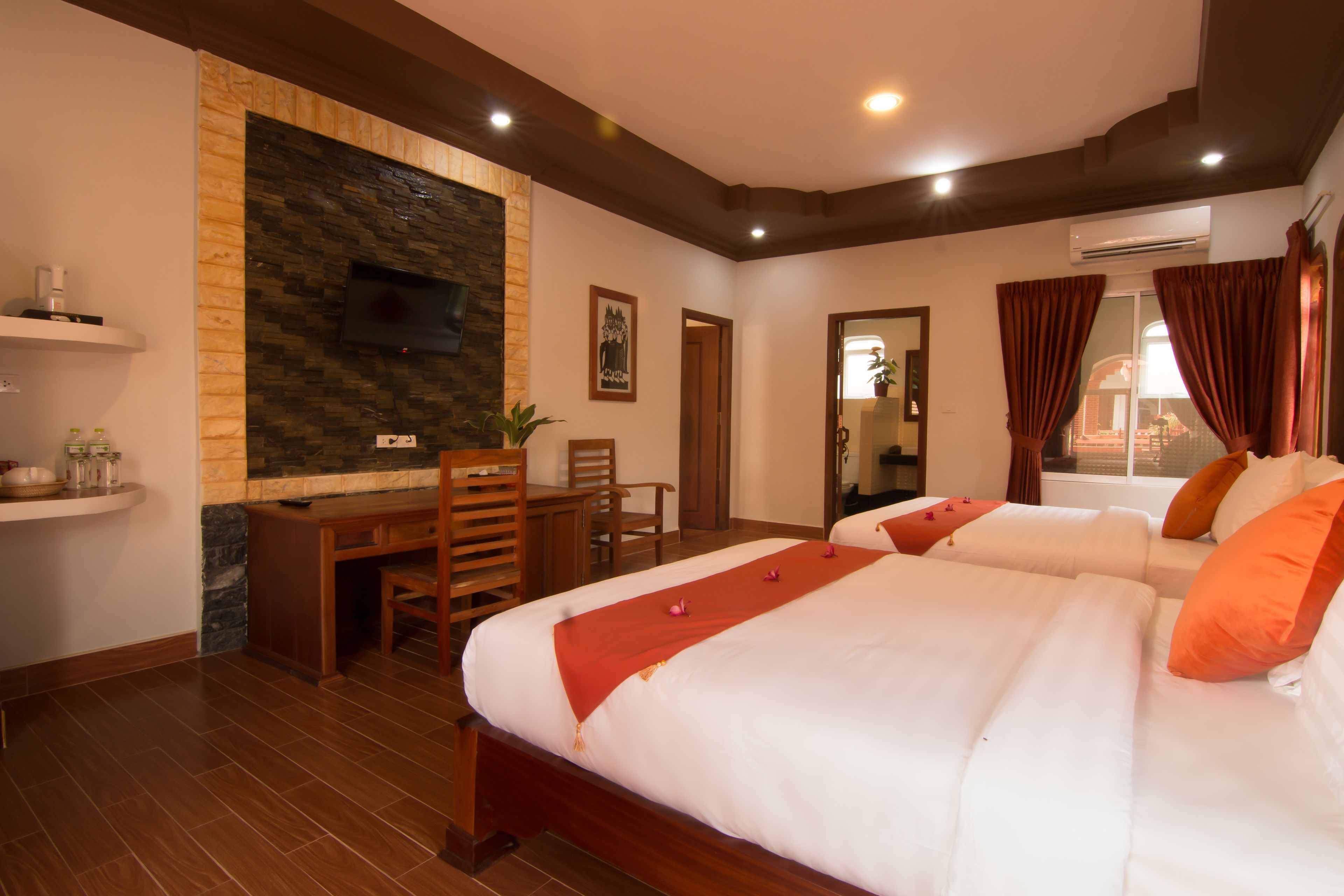 Een hotelkamer met een groot bed, een bureau en een accentmuur van steen.