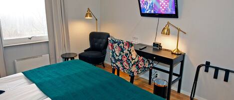 Une chambre d’hôtel avec un lit, un bureau, une chaise, une télévision et une fenêtre.