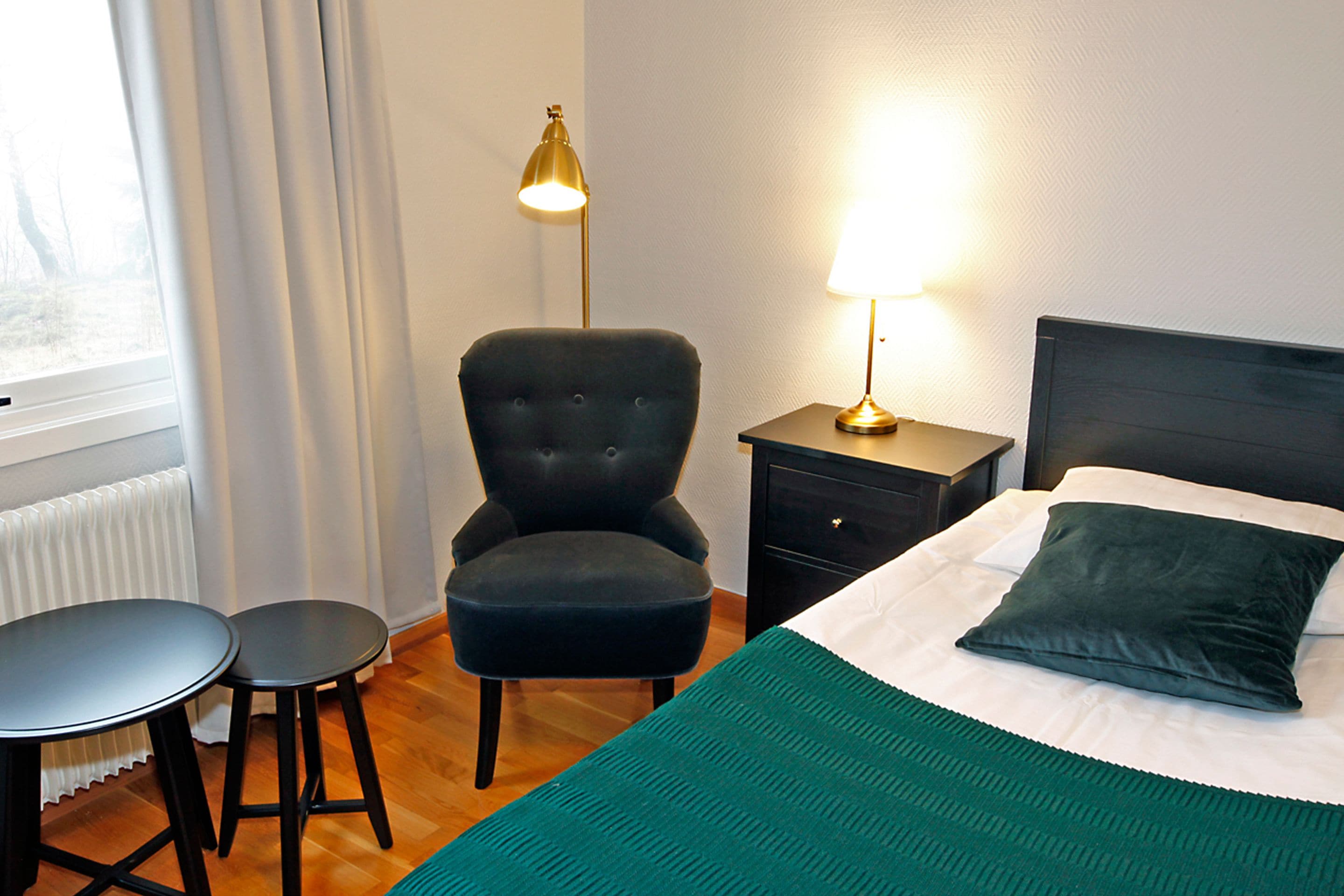 Une chambre d’hôtel avec un lit, une chaise, une table et une lampe.