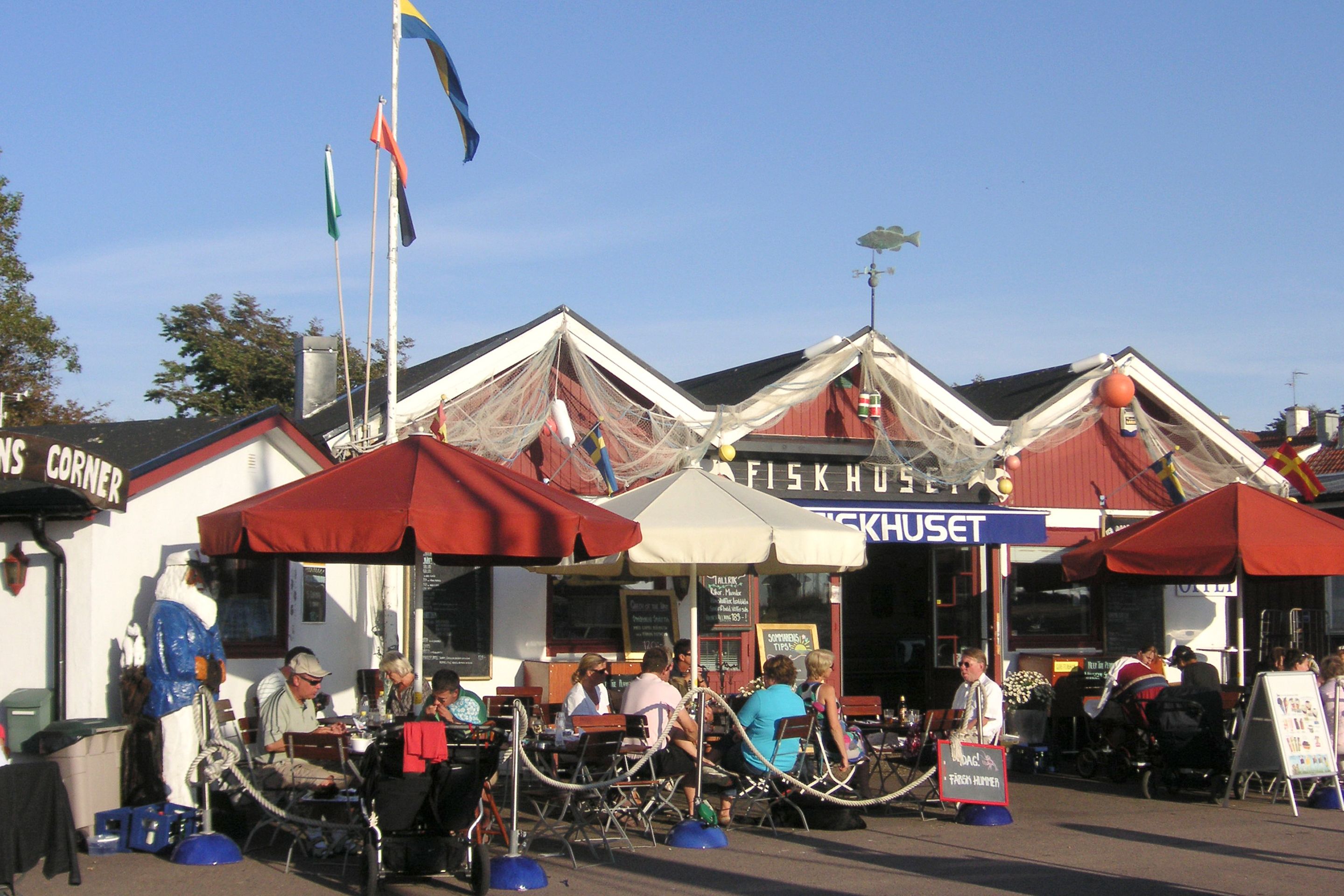 A waterfront market with outdoor seating and flags.