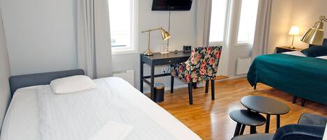 Habitación de hotel con una cama grande, un escritorio con silla, un televisor y una pequeña mesa con sillas.