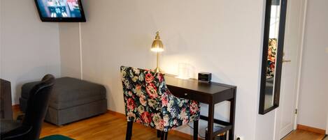 Une chambre comprenant un lit, un bureau avec une chaise, un téléviseur fixé au mur et un miroir sur la porte.