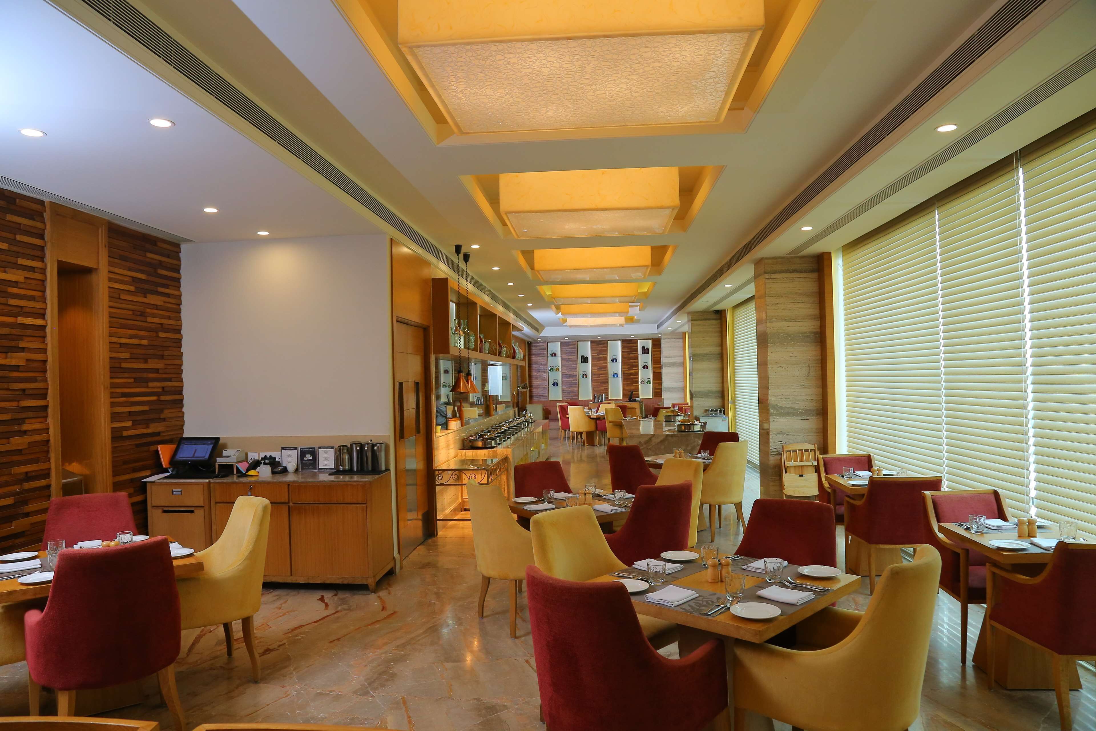 A modern restaurant with a long counter, multiple dining tables, and chairs.