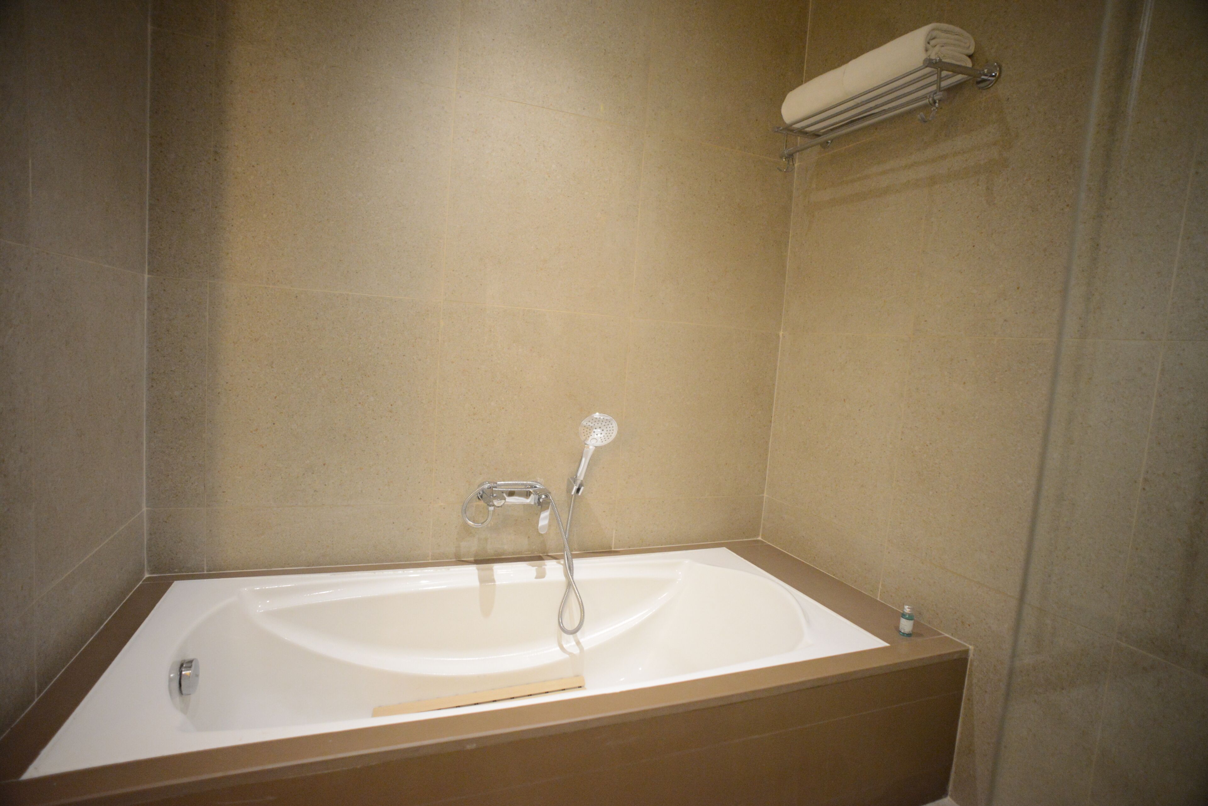 A bathroom with a bathtub, a showerhead, and a towel rack.