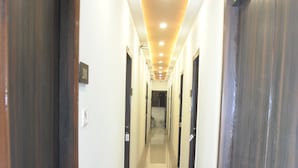 Un pasillo largo y estrecho con puertas de madera a ambos lados y suelo de baldosas.