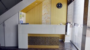 Un área de recepción con diseño moderno, que incluye un mostrador de recepción, un reloj y una pared con diseño.