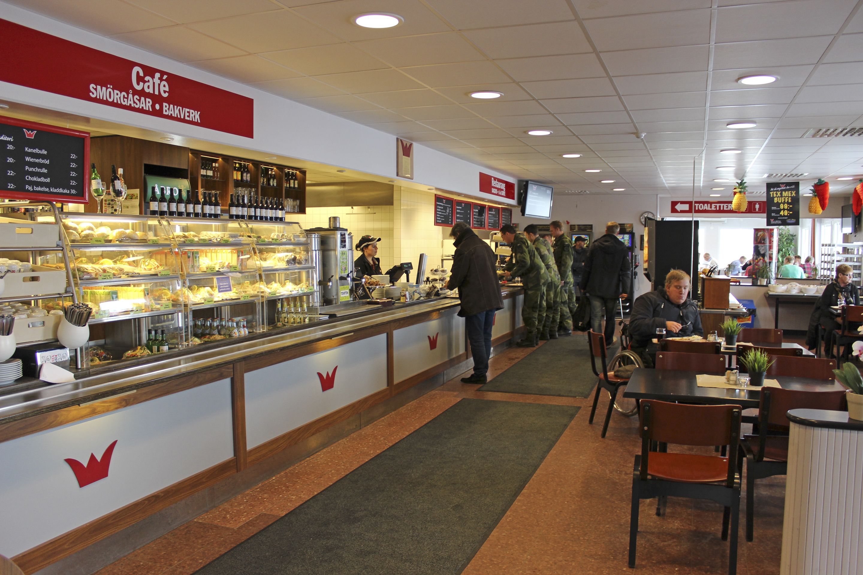 A café with a buffet counter, a menu board, and a sign for the toilet.