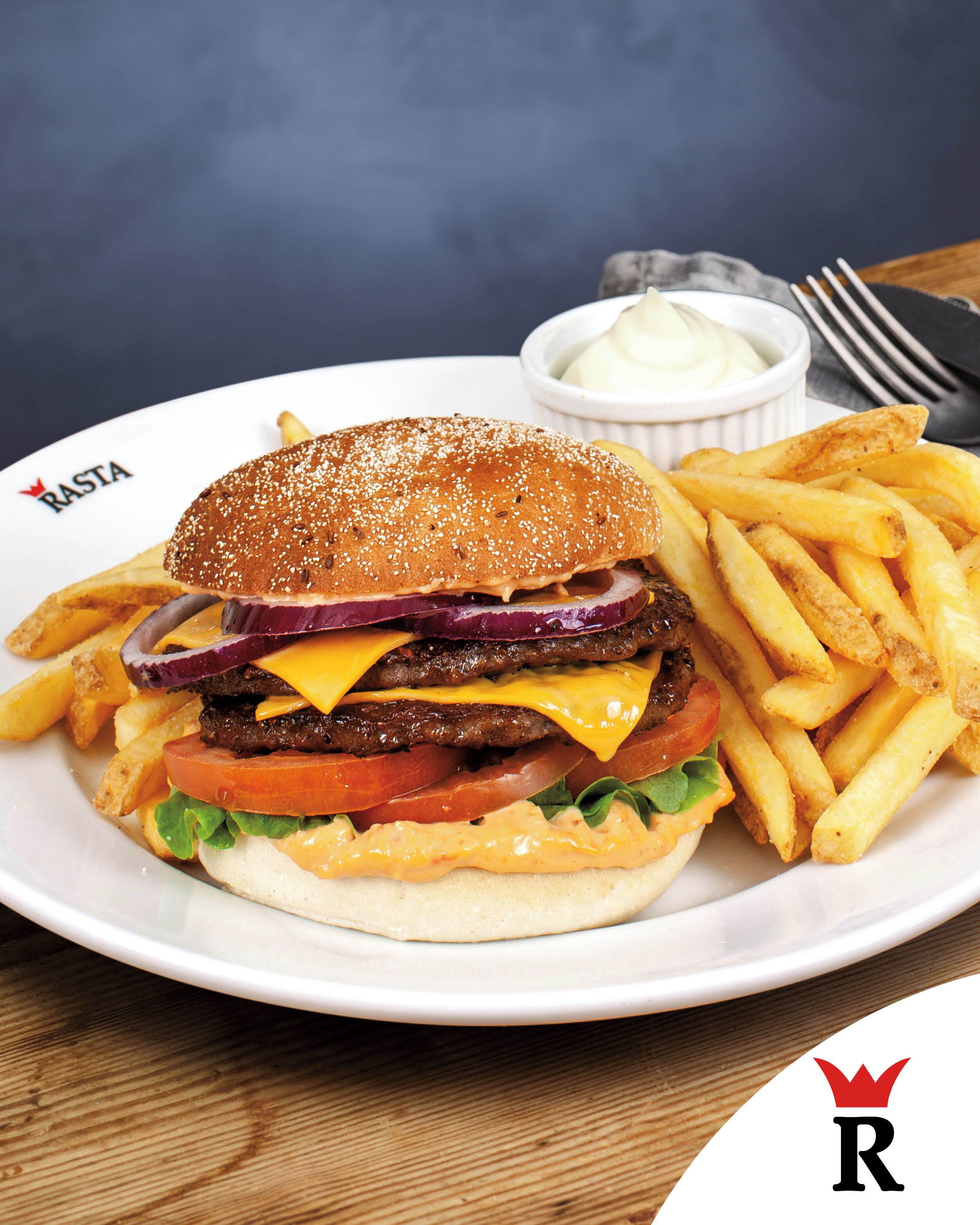 A plate with a burger and fries, a small bowl of sauce, and a fork.