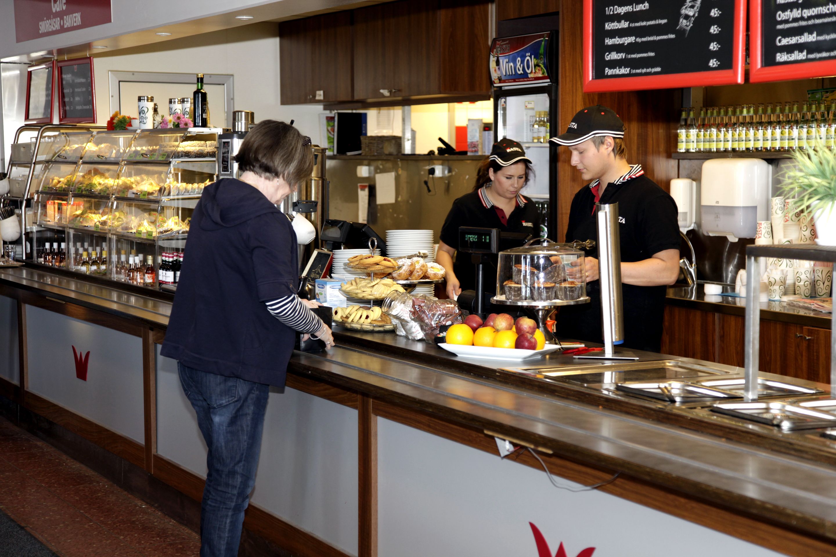 A buffet counter with various food items and a menu board in the background.