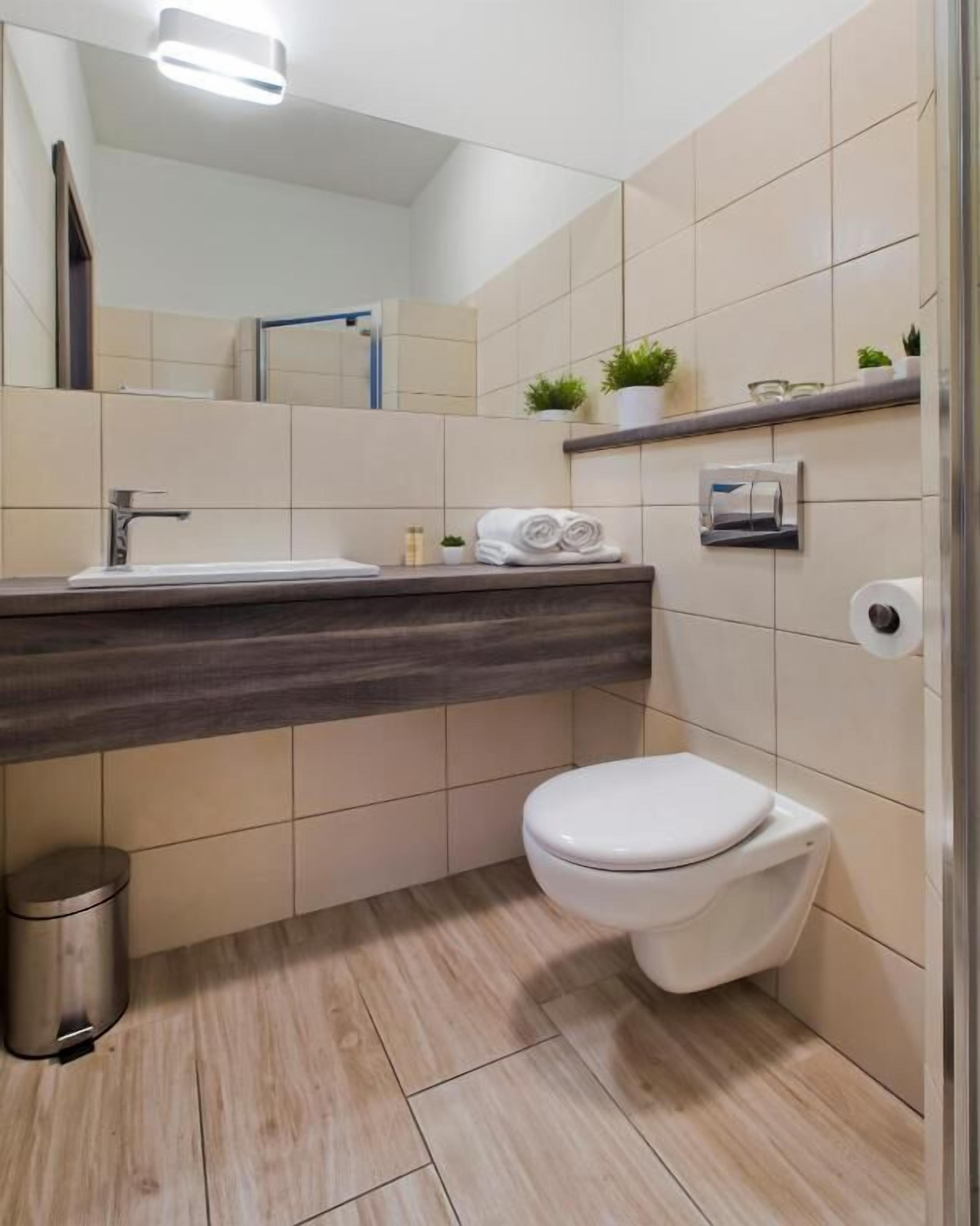 A modern bathroom with a white sink, a toilet, and a mirror.