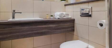 A modern bathroom with a white sink, a toilet, and a mirror.