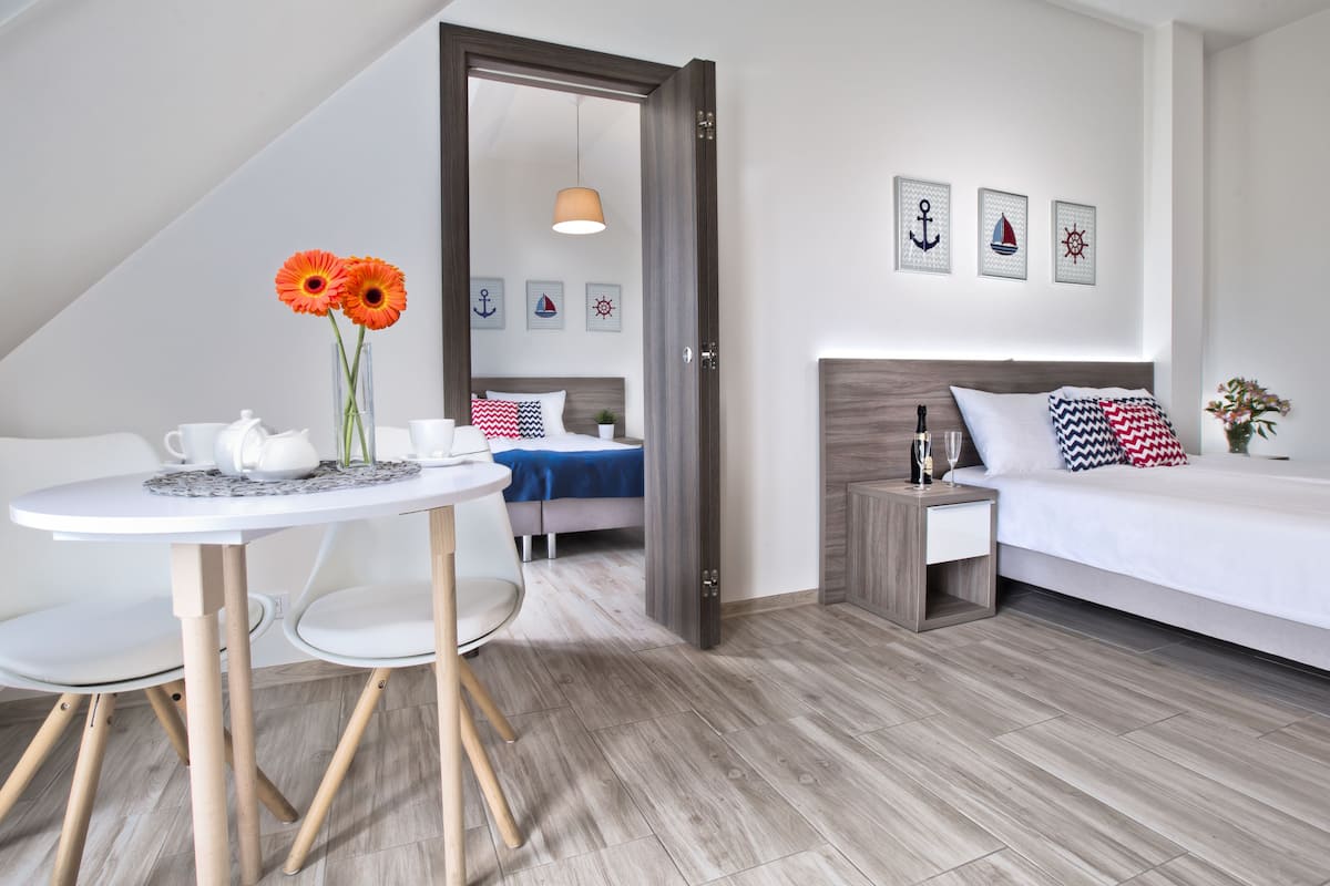 A modern bedroom with a bed, bedside table, and a small table with a teapot and cups.
