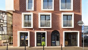 Ein modernes, mehrgeschossiges Gebäude mit Ziegelaußenwand und Fenstern in weißen Rahmen.