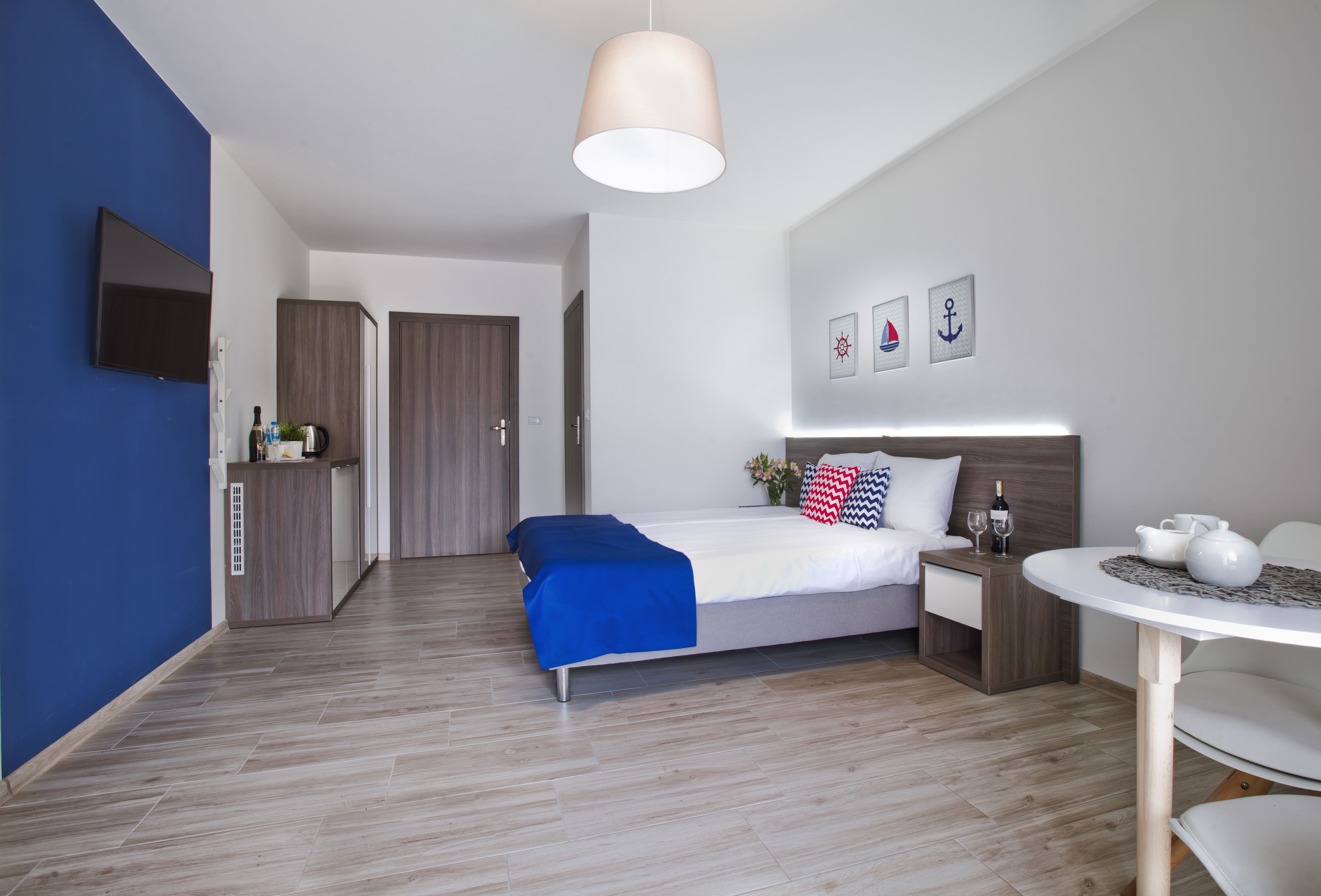 A modern hotel room with a bed, bedside table, and a small round table with a chair.