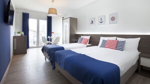 Ein Hotelzimmer mit zwei Betten, einem Fernseher, einem Schreibtisch mit Stuhl und Blick ins Freie.