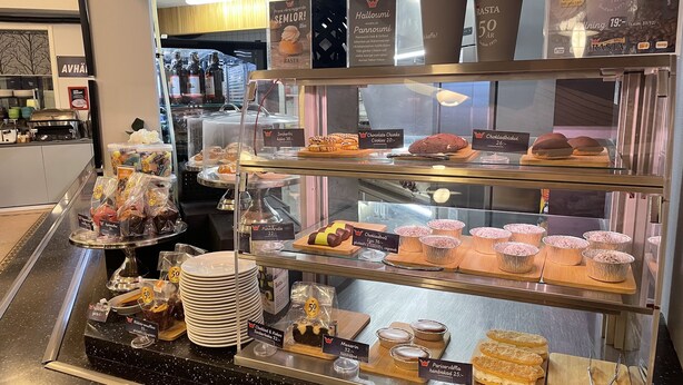 A bakery display with various pastries and desserts, including chocolate chunks, cookies, and muffins, priced at 50 AR.