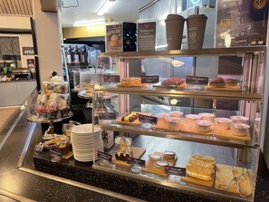A bakery display with various pastries and desserts, including chocolate chunks, cookies, and muffins, priced at 50 AR.