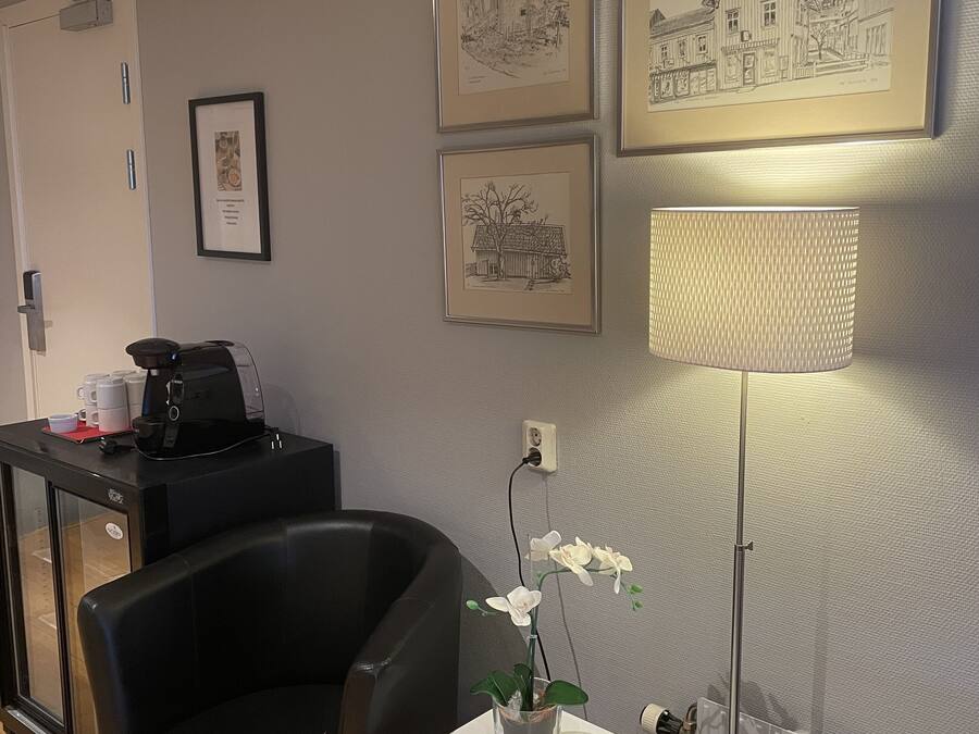 Un espace d’accueil comprenant un bureau, des chaises, des œuvres d’art encadrées et une lampe.