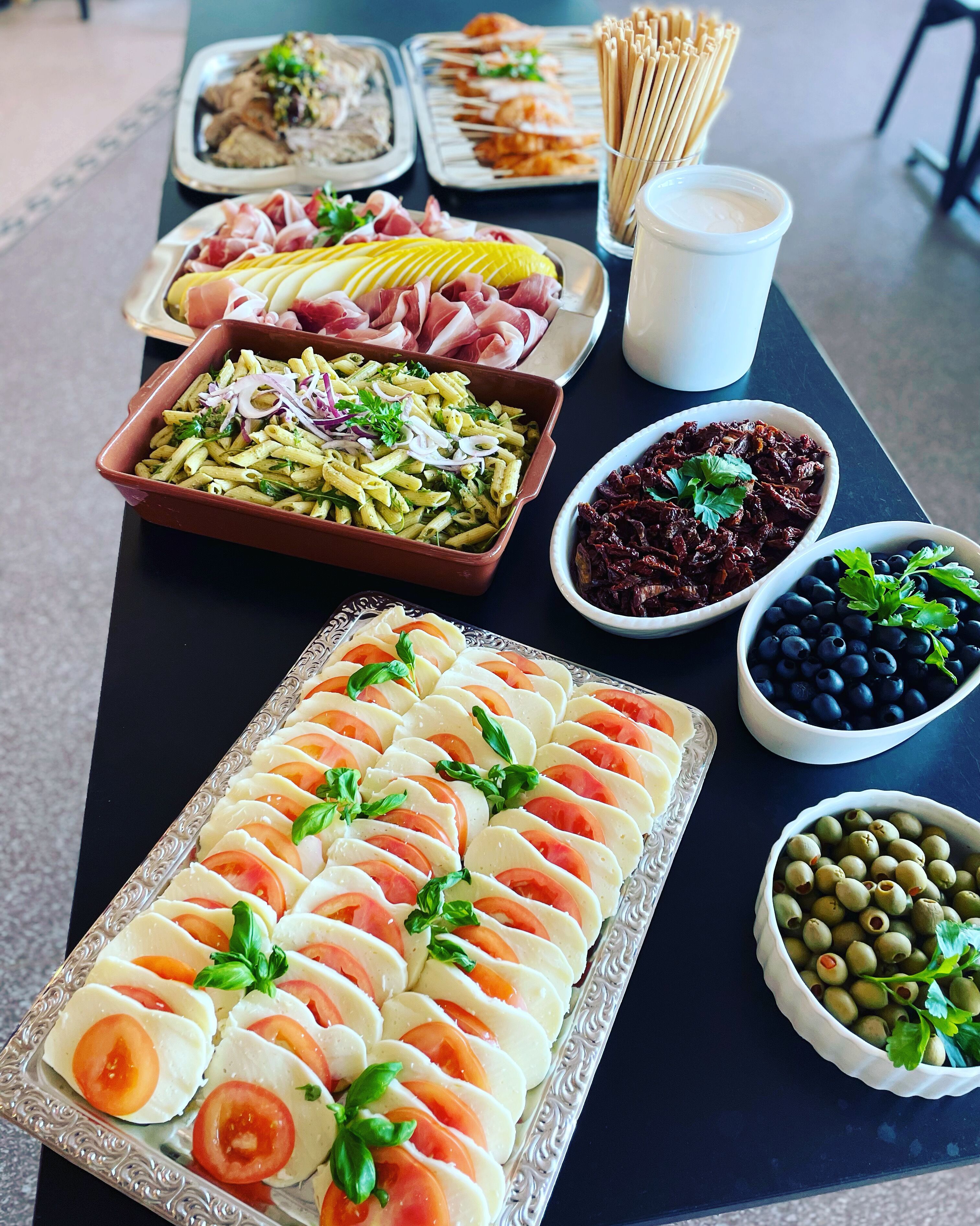 Una mesa de buffet con diversos platos, incluyendo pasta, queso y frutas.