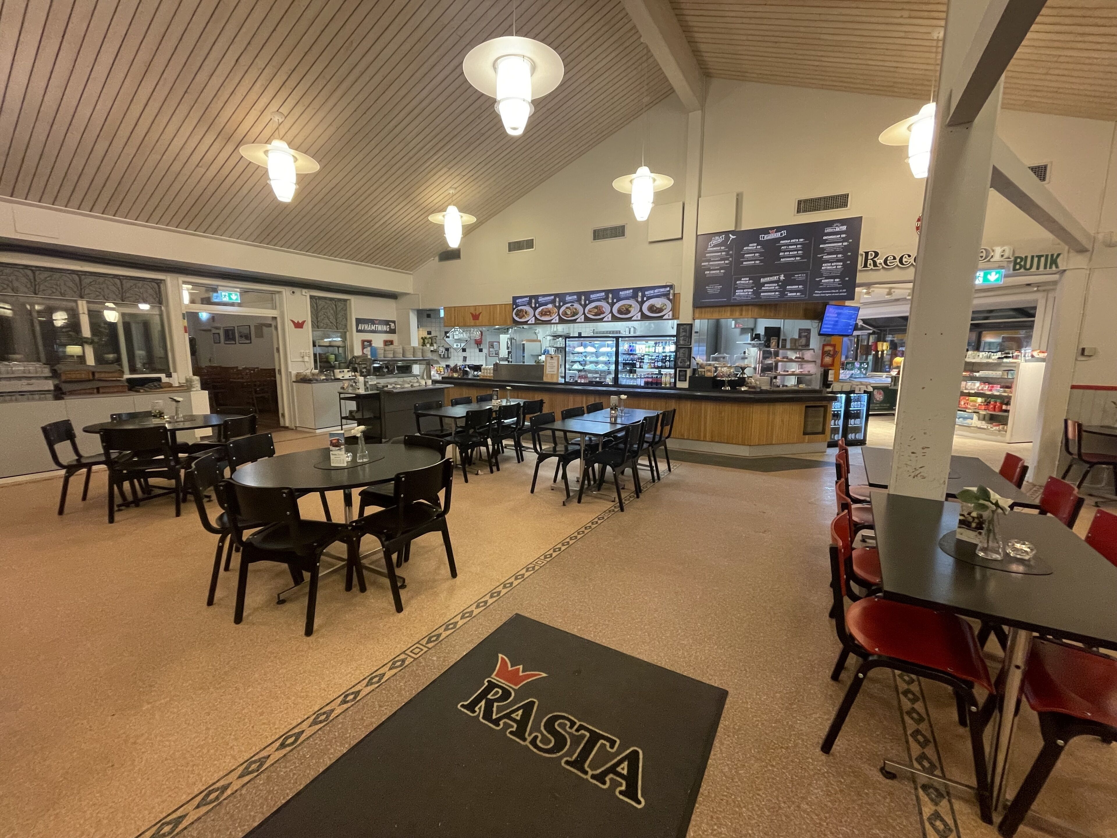Een restaurant met meerdere tafels en stoelen, een bar en een menubord.