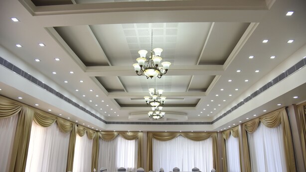A conference room with round tables, chairs, and a chandelier.