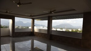 A spacious room with large windows, ceiling fans, and a reflective floor.